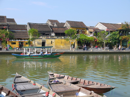 HOI AN, VIETNAM - 19TH MARCH 2018: Beautiful day in Hoi An ancient town with view of traditional boats, yellow houses by the river, and touristsのeditorial素材
