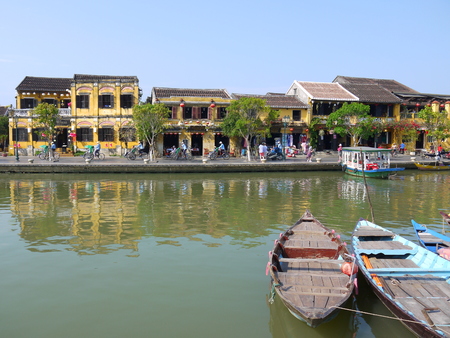 HOI AN, VIETNAM - 19TH MARCH 2018: Beautiful day in Hoi An ancient town with view of traditional boats, yellow houses by the river, and touristsのeditorial素材