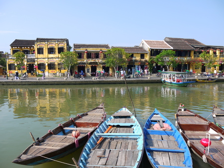 HOI AN, VIETNAM - 19TH MARCH 2018: Beautiful day in Hoi An ancient town with view of traditional boats, yellow houses by the river, and touristsのeditorial素材