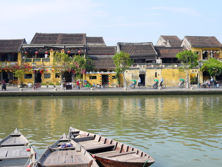 HOI AN, VIETNAM - 19TH MARCH 2018: Beautiful day in Hoi An ancient town with view of traditional boats, yellow houses by the river, and touristsのeditorial素材