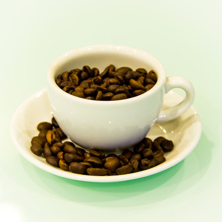 The coffee beans in the ceramic cup on white background.の写真素材