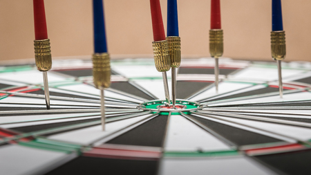 Darts hitting in the target center of dartboard.