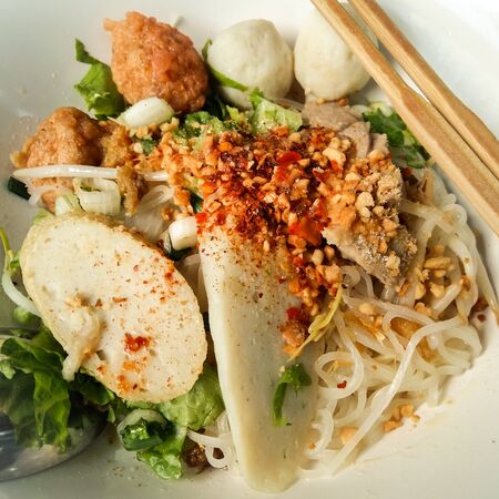 Closeup of Thai noodles in white bowl and chopsticks