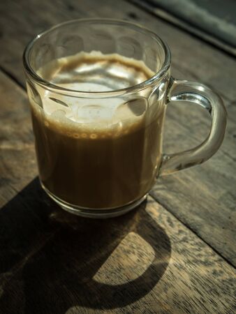 Cup of coffee with shadow on the wooden tableの写真素材