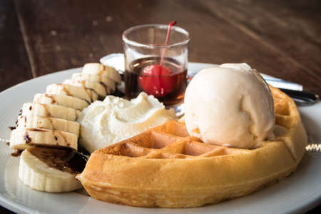 Close up of vanilla ice cream with a waffle on a white plateの写真素材