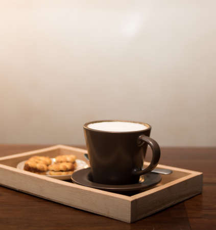 Hot coffee in a ceramic cup on a wooden plate.の写真素材