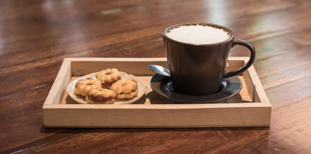 Hot coffee in a ceramic cup on a wooden plate.の写真素材