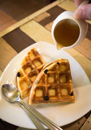 Raisin waffle on a white plate with sweet honey. Selective focusの写真素材