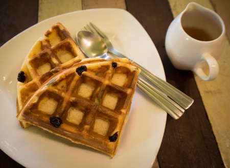 Raisin waffle on a white plate with sweet honey. Selective focusの写真素材
