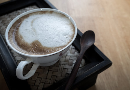 Hot coffee in a ceramic cup on a wooden tray.の写真素材