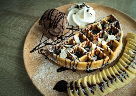 Close up of chocolate ice cream with a waffle on a wooden plateの写真素材