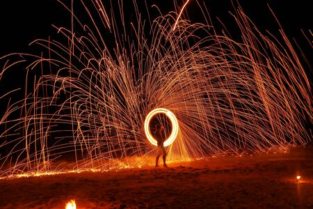 A man is showing swing fire dancing on the beach at nightの写真素材