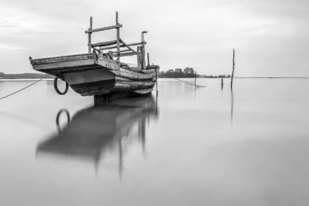 Abandoned Fisherman boat on black and white at early cloudy morningの写真素材