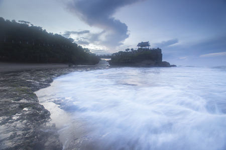 Sea waves crashing over rocks on the wild stone beach in sunset time and seafoam created by the agitation of seawater in the moment of ocean waves crashing against rocks.の写真素材