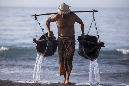 BALI, INDONESIA - May 8,2015 : Unidentified local people work as natural salt farmer at Kasumba Beach, Bali. He collecting sea water and make salt naturally.のeditorial素材
