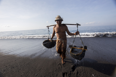 BALI, INDONESIA - May 8,2015 : Unidentified local people work as natural salt farmer at Kasumba Beach, Bali. He collecting sea water and make salt naturally.のeditorial素材