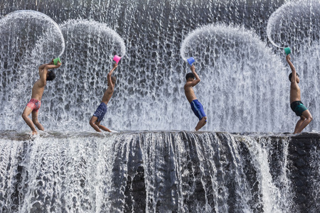 BALI, INDONESIA- June 2, 2014: Unidentified boys were having fun by playing water in an artificial dam on the Tukad Unda dam, Bali, Indonesia. Bali island is a popular tourist destination in the worldのeditorial素材