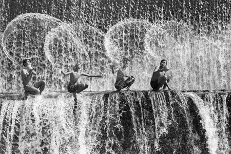 BALI, INDONESIA- June 2, 2014: Unidentified boys were having fun by playing water in an artificial dam on the Tukad Unda dam, Bali, Indonesia. Bali island is a popular tourist destination in the worldのeditorial素材