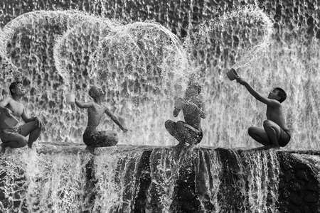 BALI, INDONESIA- June 2, 2014: Unidentified boys were having fun by playing water in an artificial dam on the Tukad Unda dam, Bali, Indonesia. Bali island is a popular tourist destination in the worldのeditorial素材