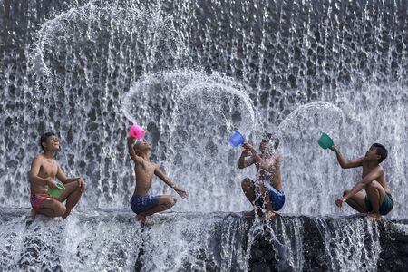 BALI, INDONESIA- June 2, 2014: Unidentified boys were having fun by playing water in an artificial dam on the Tukad Unda dam, Bali, Indonesia. Bali island is a popular tourist destination in the worldのeditorial素材