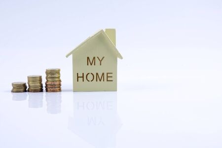 Wooden house model with pile of coin and calculator. House finance concept.の写真素材