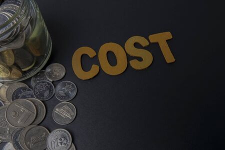 Coins in the glass with words cost . Money and business saving concept.の写真素材
