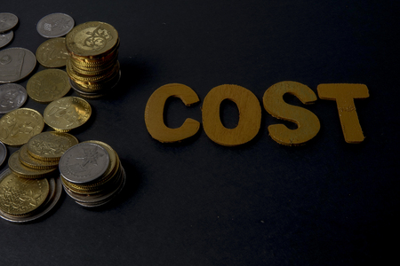 Coins in the glass with words cost . Money and business saving concept.の写真素材