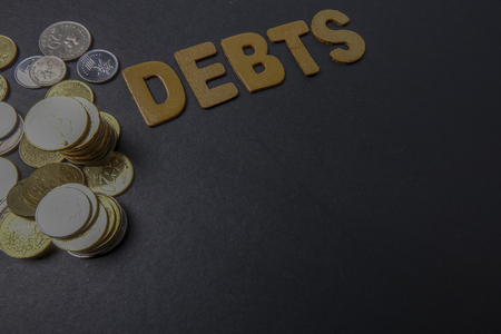 Coins and word of DEBTS on black backgroundの写真素材