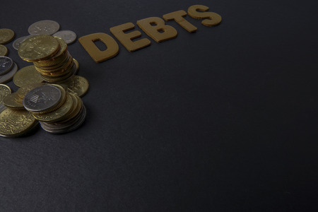 Coins and word of DEBTS on black backgroundの写真素材