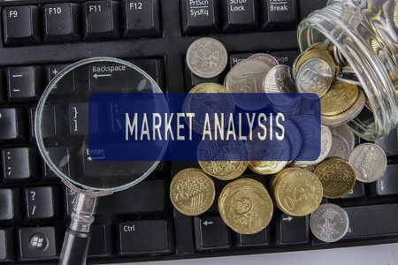 Magnify glass and coins on keyboard. Business analysis concept on cloud words.の写真素材