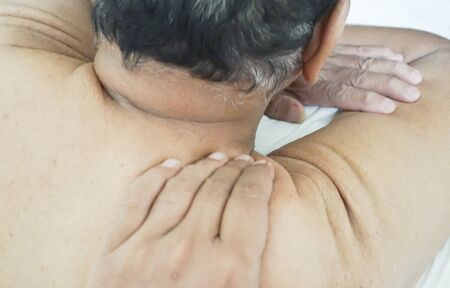 Senior man receiving a back massage. Low light and selective focusの写真素材