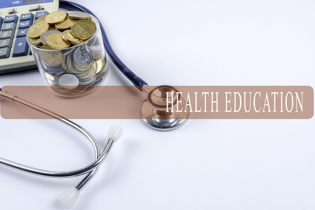 a stethoscope with piles of coins and calculator - healthcare cost conceptの写真素材