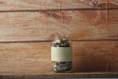 Coins in jar over wooden background. Saving conceptの写真素材