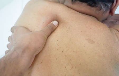 Senior man receiving a back massage. Low light and selective focusの写真素材