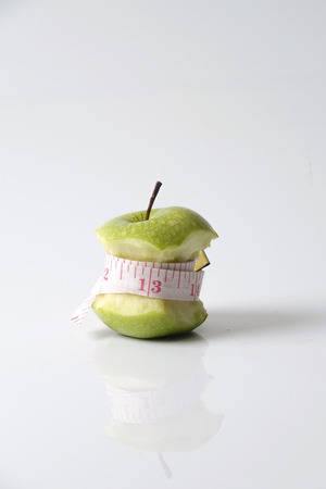 Close up of green apple with measuring tape isolated on white background.の写真素材