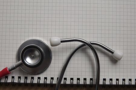 Red stethescope on wooden background. Medical and health care concept.