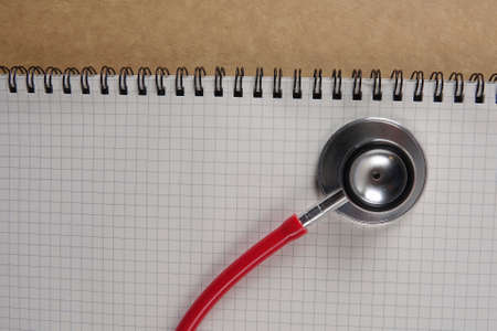 Red stethescope on wooden background. Medical and health care concept.の写真素材