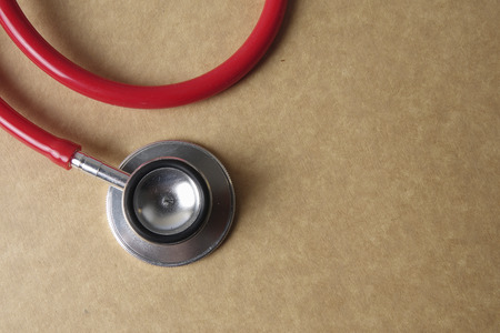 Red stethescope on wooden background. Medical and health care concept.の写真素材