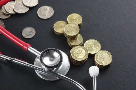 Red stethoscope,coin and puzzle on black. Medical concept.の写真素材