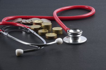 Red stethoscope,coin and puzzle on black. Medical concept.の写真素材