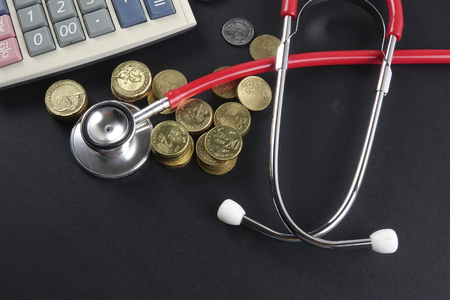 Red stethoscope and coins on black background. Medicalの写真素材