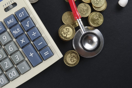 Red stethoscope and coins on black background. Medicalの写真素材