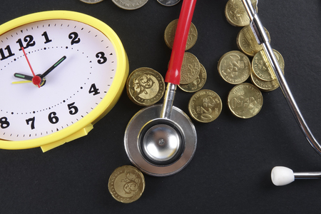 Red stethoscope and coins on black background. Medicalの写真素材