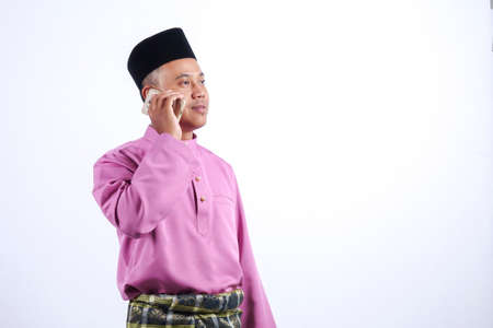Man in traditional clothing with smartphone celebrate Eid Fitr.の写真素材