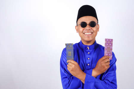 Man in traditional clothing cheerful with money packet during celebrate Eid Fitr.の写真素材