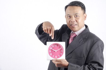 Asian businessman standing with a clock, concept of time manage or planningの写真素材