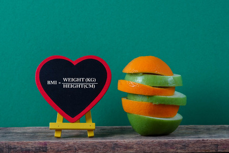 A conceptual fruit of fitness with green apple and orange and a measuring tape with BODY MASS INDEX (BMI) formula.の写真素材