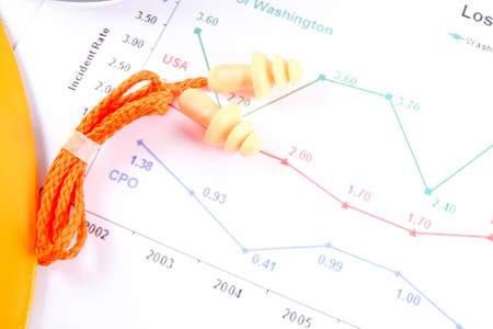 Yellow hardhat safety helmet,safety glass and ear plug over accident statistic graph as a background. Industrial safety and health conceptual.の写真素材