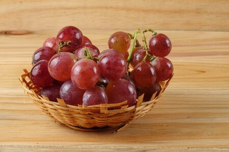Red grape on the basket over wooded background.の写真素材