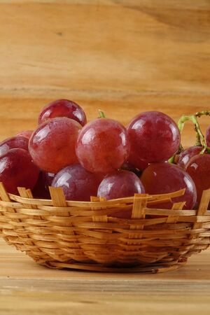 Red grape on the basket over wooded background.の写真素材